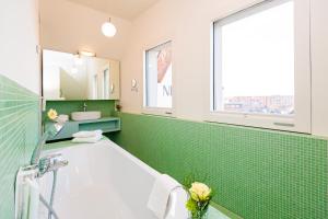 ヴィスマールにあるホテル ニュー オリンズの緑のタイル張りのバスルーム(バスタブ、シンク付)