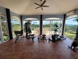 un gimnasio con cintas de correr y bicicletas estáticas en una sala con ventanas en Luxury Villa with Separate Guest house and 360view, en Quepos