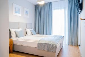 Schlafzimmer mit einem großen Bett und blauen Vorhängen in der Unterkunft Blue Mare Solna 205 in Kołobrzeg