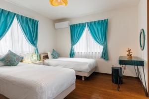 duas camas num quarto com cortinas azuis em Yomitan kuba house em Yomitan
