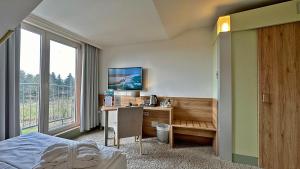 Schlafzimmer mit einem Schreibtisch, einem Bett und einem Fenster in der Unterkunft Hotel & SPA Sommerfeld - Adults Only in Kremmen
