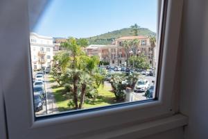 a window with a view of a parking lot with palm trees at Affittacamere Piazza Mazzini in Terracina