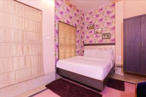 ein Schlafzimmer mit einem Bett und einer lila Wand in der Unterkunft FabHotel Poorv Sight in Varanasi