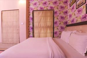 ein Schlafzimmer mit einem Bett mit rosa Blumen an der Wand in der Unterkunft FabHotel Poorv Sight in Varanasi