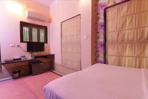 Schlafzimmer mit einem weißen Bett und einem TV in der Unterkunft FabHotel Poorv Sight in Varanasi
