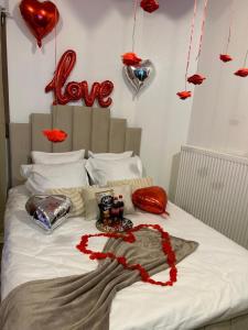 a bed with red hearts on the wall and balloons at Au cœur du nouveau cergy Aren park in Cergy