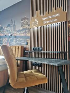 a table and a chair in front of a wall at Przytulny apartament Brooklyn Centrum miasta Rzeszów - Podwisłocze 38 in Rzeszów +2 photos