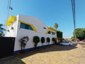 a white house with a car parked in front of it at Hotel Indi Suíte Standard in Ribeirão Preto