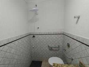 a bathroom with a toilet in a tiled room at Hotel Indi Suíte Standard in Ribeirão Preto