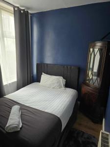 a bedroom with a bed with a blue wall at ROSE in Blackpool