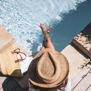 Una donna con un cappello di paglia seduta accanto a una piscina di Château Mentone a Masseboeuf