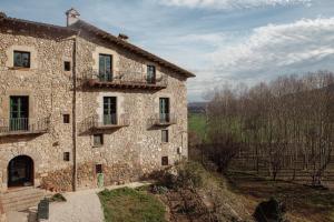 un antiguo edificio de piedra en un campo con árboles en Mas Toralles, en Sant Privat de Bas