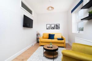 een woonkamer met een gele bank en een tafel bij 2 bedroom flat near Tottenham Hotspur Stadium in Londen