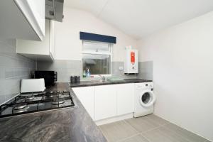 a kitchen with a stove and a washing machine at 2 bedroom flat near Tottenham Hotspur Stadium in London