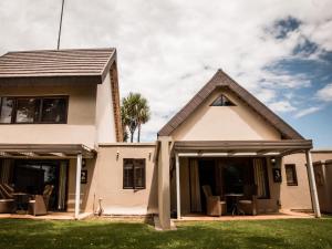 una casa blanca con sillas y una palmera en Bona Bona Game Lodge, en Wolmaranstad