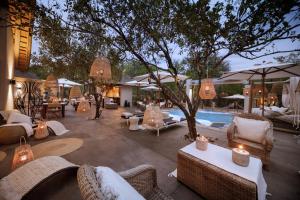 un patio con sillas, mesas y una piscina en African Flair Boutique Safari Lodge en Hoedspruit