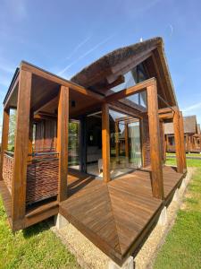 ein Holzhaus mit einer Terrasse im Gras in der Unterkunft Domki Kuter Port in Gdów