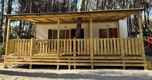 a small house with a wooden deck in the yard at Camping Village Mare Pineta in Paestum