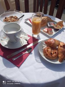 a table with a plate of food and a cup of orange juice at Hôtel du tilleul in Corps