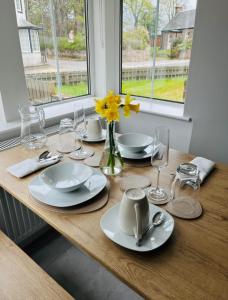 a table with plates and glasses and a vase with flowers at Altonhill House - room only in Nairn