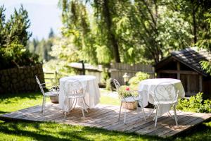 2 tables et chaises assises sur une terrasse en bois dans l'établissement Hotel Tann, à Collalbo