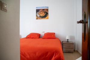 - un lit avec des draps orange et une photo sur le mur dans l'établissement Bungalow à Orihuela Costa en Espagne, à Orihuela 83 autres photos