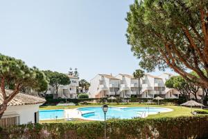 a swimming pool with trees and apartments in the background at Reliquia 3 in Novo Sancti Petri