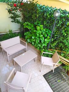twee witte tafels en stoelen naast een heg bij Appartamento giardino in Rapallo