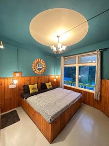 a bedroom with a large bed and a large chandelier at Whoopers Hostel Jibhi in Jibhi