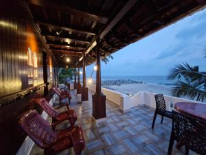 a porch with chairs and tables and a view of the ocean at Seabreeze Marari in Alleppey