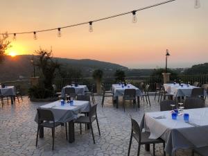 um restaurante com mesas e cadeiras com o pôr-do-sol ao fundo em Valle dei Greci Rooms em Peschici