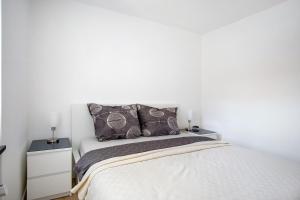 a white bedroom with a bed and two night stands at Im Spatzennest in Inzell