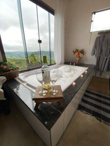 uma casa de banho com banheira e 2 copos de vinho numa mesa em Pousada Vitória em Gonçalves