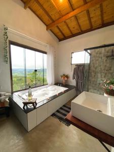 uma grande casa de banho com uma grande banheira e uma grande janela em Pousada Vitória em Gonçalves