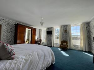 een slaapkamer met een bed, een stoel en ramen bij Trewardale in Bodmin