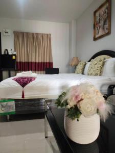 una camera da letto con un letto e un tavolo con dei fiori di ห้องพักนครราชสีมาใกล้เซ็นทรัล The Rich Room a Ban Pra Dok