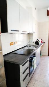 uma cozinha com armários brancos e um lavatório em Guest House Gobetti em Reggio Emilia