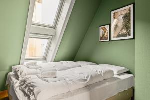a bed in a green room with two windows at Dinbnb Apartments I Shopping, Cafés And Attractions At Your Doorstep! in Bergen