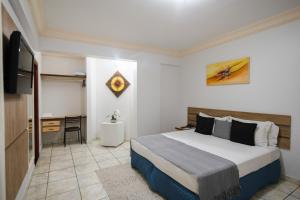 Dormitorio con cama, escritorio y TV en Havana Palace Hotel, en Uberaba