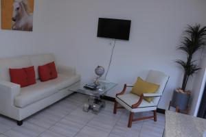 uma sala de estar com um sofá e duas cadeiras e uma televisão em No 2 on Cladon Jadde Apartments em Chartwell