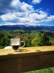 um copo de vinho sentado num carril de madeira com vista em Glamping ZAZEN em Drumu Carului