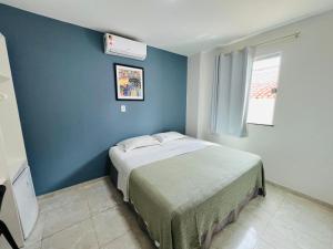 1 dormitorio con 1 cama con pared azul en Belaris Hotel antes Hotel Costa do Calhau, en São Luís