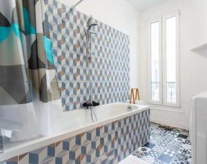 een badkamer met een bad en een tegelwand bij 678 Suite Raspail - Superbe Appartement in Levallois-Perret
