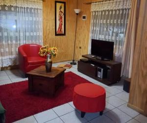 uma sala de estar com uma cadeira vermelha e uma televisão em Parcela 7 em Quillón