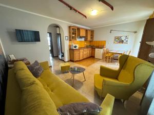 a living room with a yellow couch and a kitchen at Zakopane - Apartament Chomikówka in Zakopane