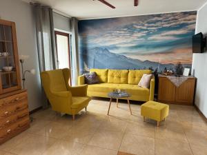 a living room with a yellow couch and a painting at Zakopane - Apartament Chomikówka in Zakopane