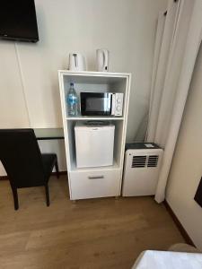 un piccolo armadio bianco con forno a microonde e sedia di Palmar Rooms a Funchal