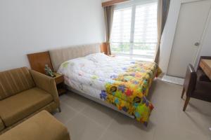 a bedroom with a bed and a chair and a window at Condo I -House Laguna Garden RCA - Outer CBD in Bangkok
