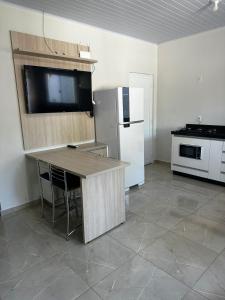 a kitchen with a refrigerator and a table with a television at Casa Cataratas in Foz do Iguaçu