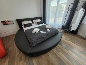 um quarto com uma cama com um repousa-pés preto em L'Hyper Centre - Netflix & Wifi - Lit Haut de Gamme & Sofa Tantra - check-in 24H24 - GoodMarning em Châlons-en-Champagne